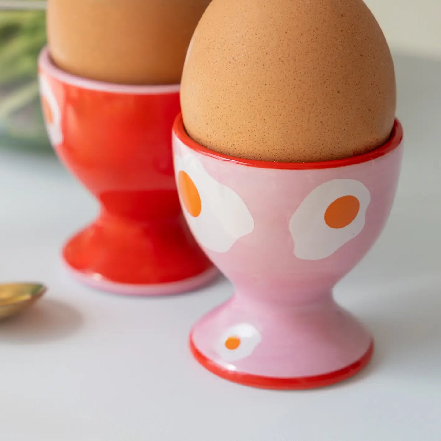 Coquetiers girly en forme d'œuf au plat sur fond blanc