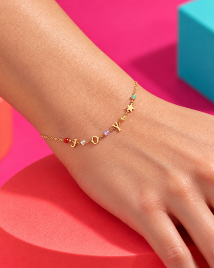 Bracelet doré JOY aux perles colorées et étoile, porté au poignet