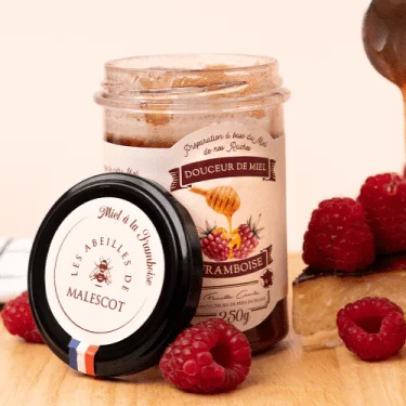 Pot de miel à la framboise avec texture lisse et brillante.