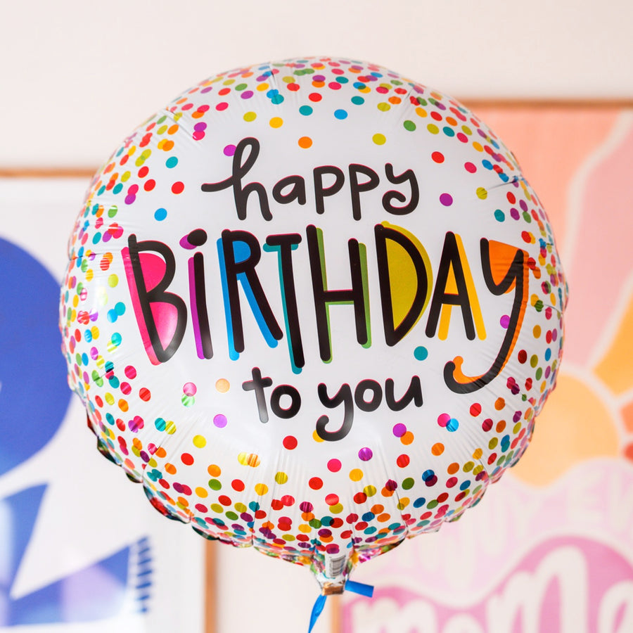 Ballon 'Happy Birthday' avec confettis colorés en gros plan.