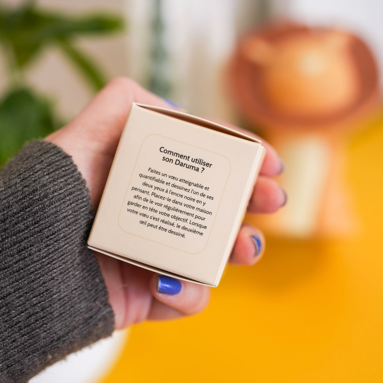 Daruma japonais en boîte, motif traditionnel et coloré.