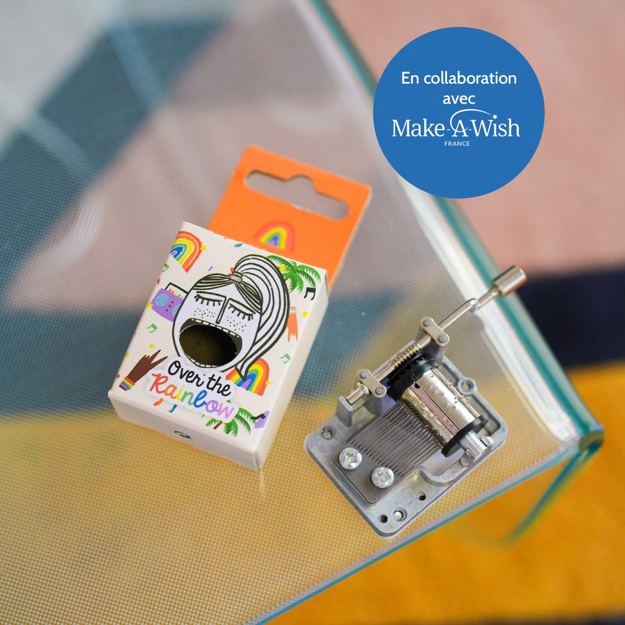 Boîte à musique avec motif coloré et manivelle visible.