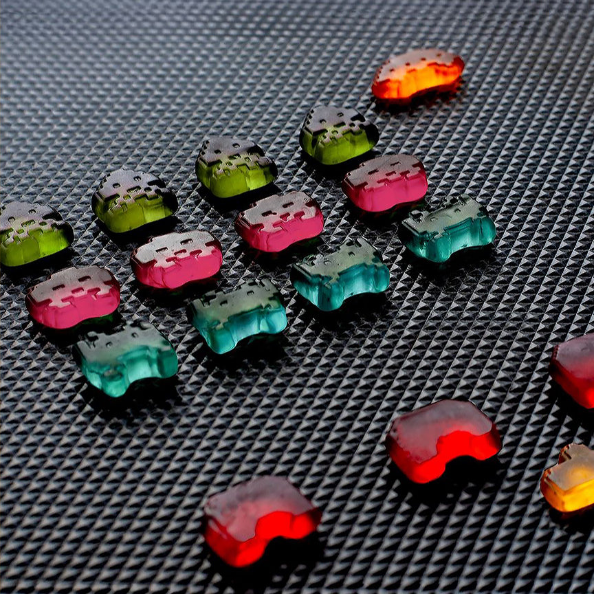 Bonbons Space Invaders en forme d'aliens colorés sur fond clair.