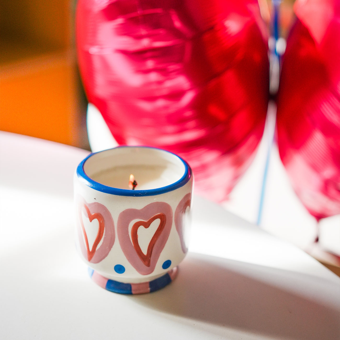 Bougie en céramique peinte à la main avec motifs de cœurs.