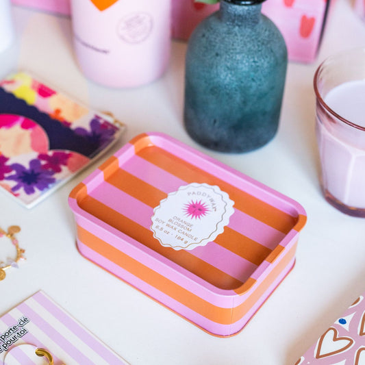 Bougie Ă 2 mĂšches avec rayures orange et rose, motif soleil.