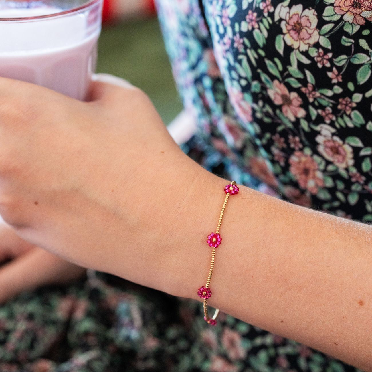 Bracelet avec marguerites roses et détails dorés en gros plan.