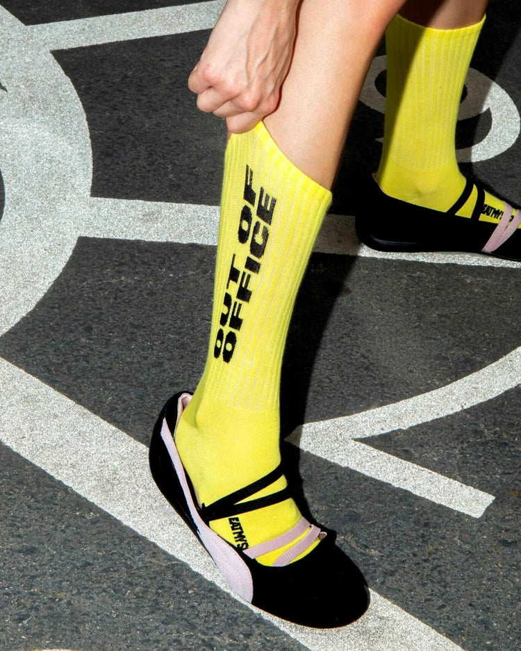 Chaussettes jaune vif à message noir, ajustées sur des jambes en mouvement