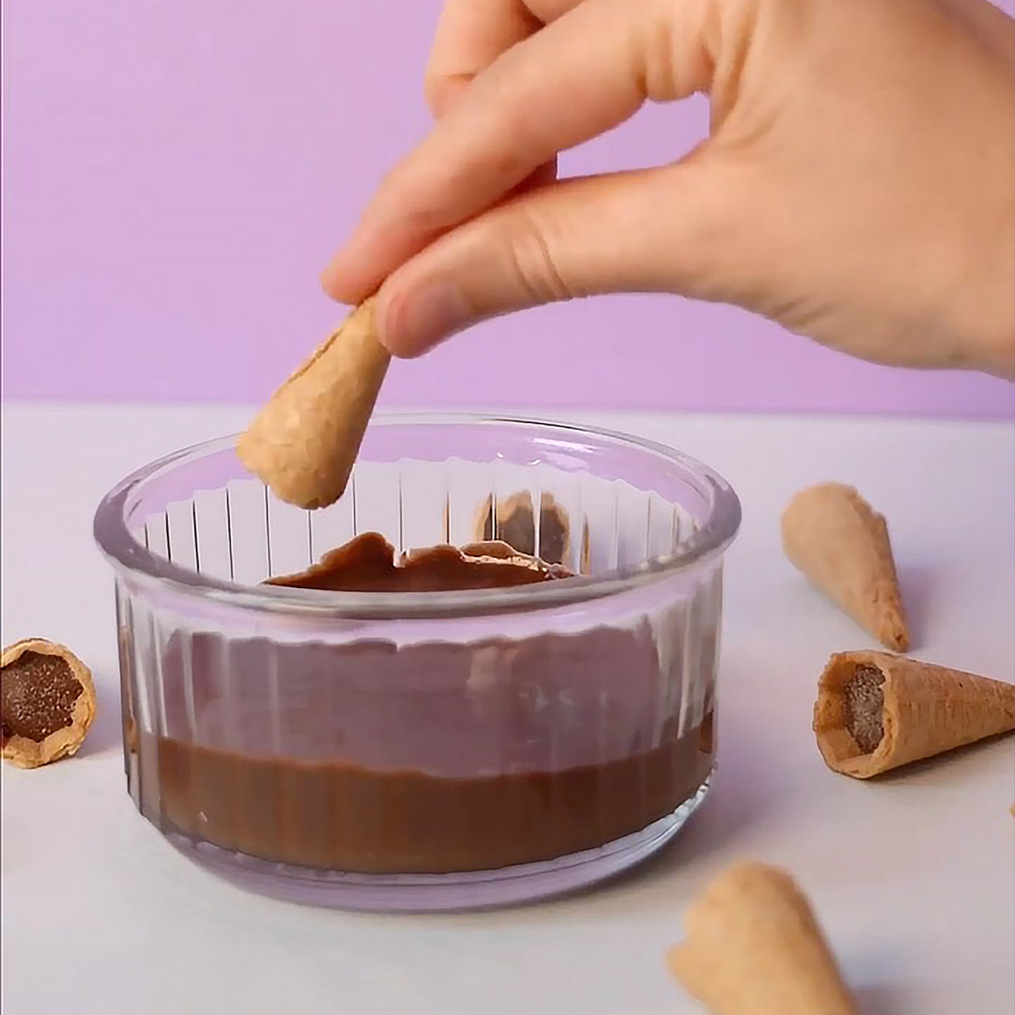Mini cônes fourrés au chocolat sur fond blanc, vue de dessus.