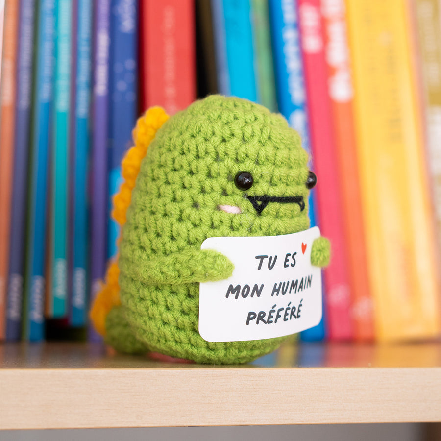 Dino en crochet tenant une pancarte avec un message affectueux.