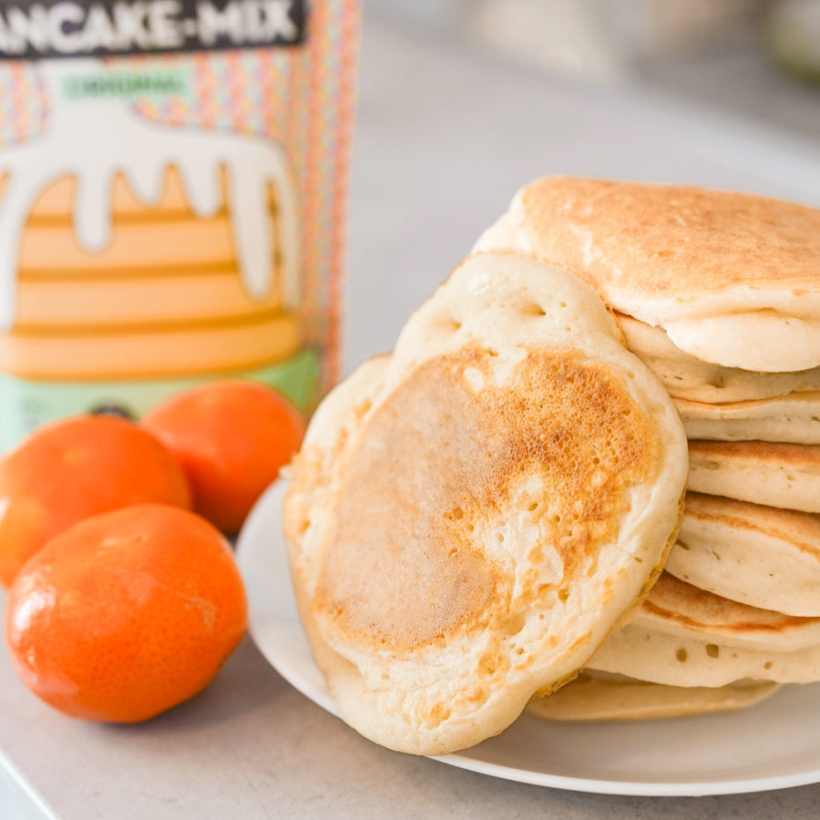 Kit DIY pancakes avec ustensiles et mélange en vue aérienne.