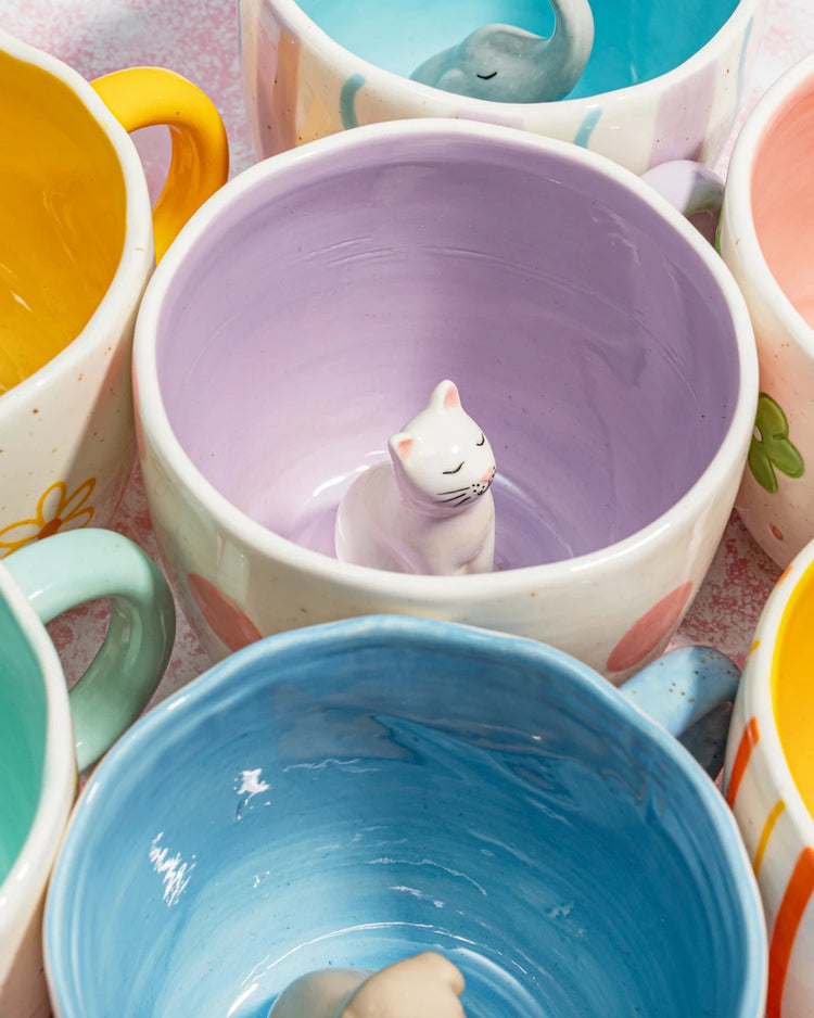 Mug rose et blanc avec un chat caché à l'intérieur