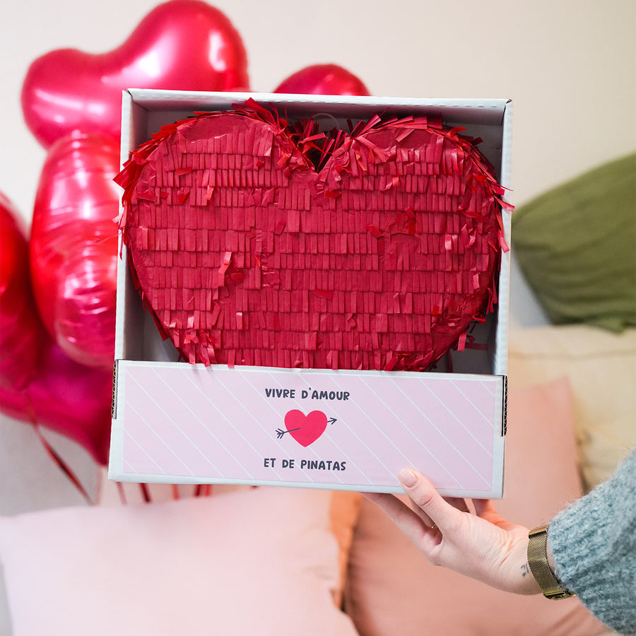Piñata en forme de cœur avec des détails colorés.