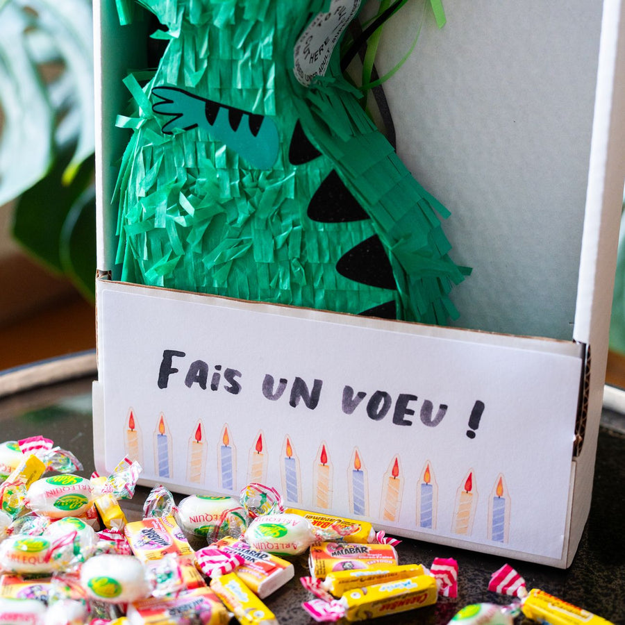Piñata dinosaure colorée avec bonbons visibles à l'intérieur.