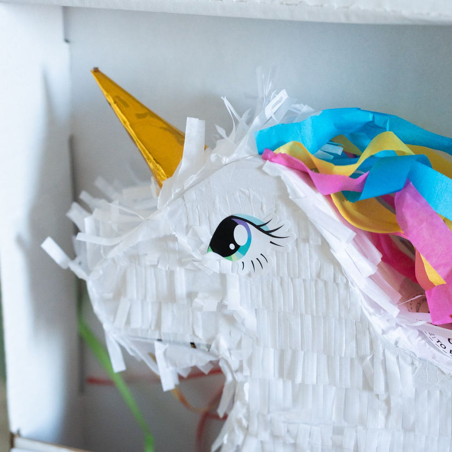 Piñata licorne colorée avec bonbons, vue de côté.