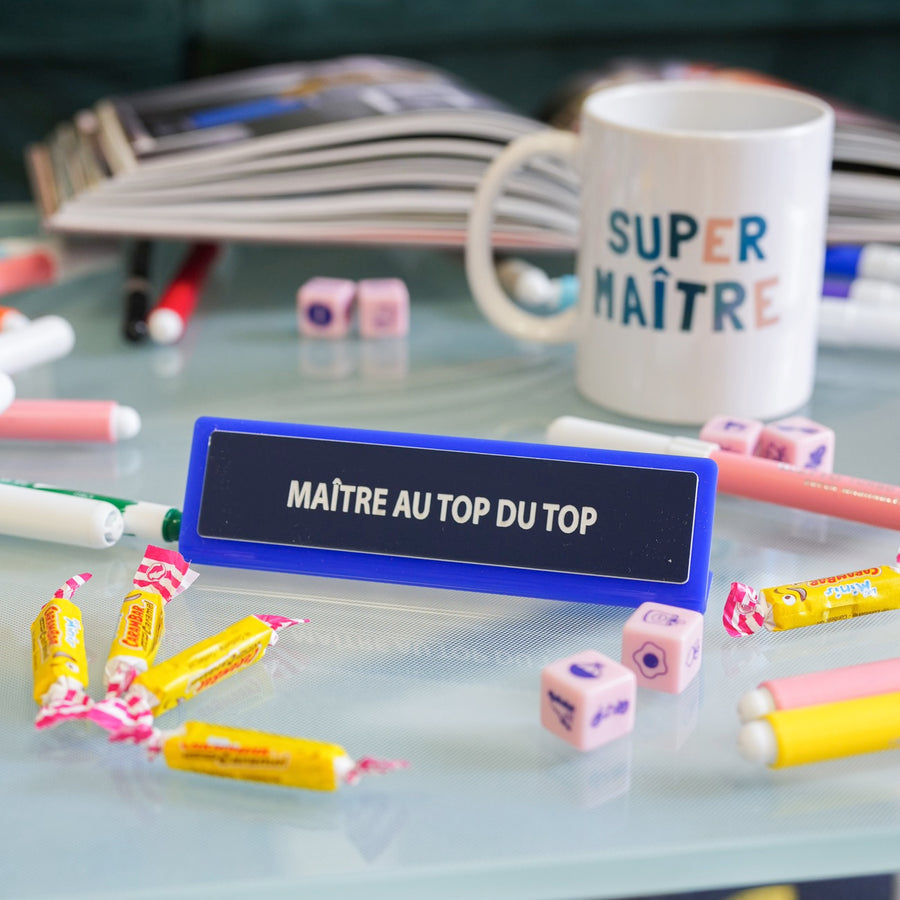 Plaque de bureau humoristique avec texte coloré sur fond clair.