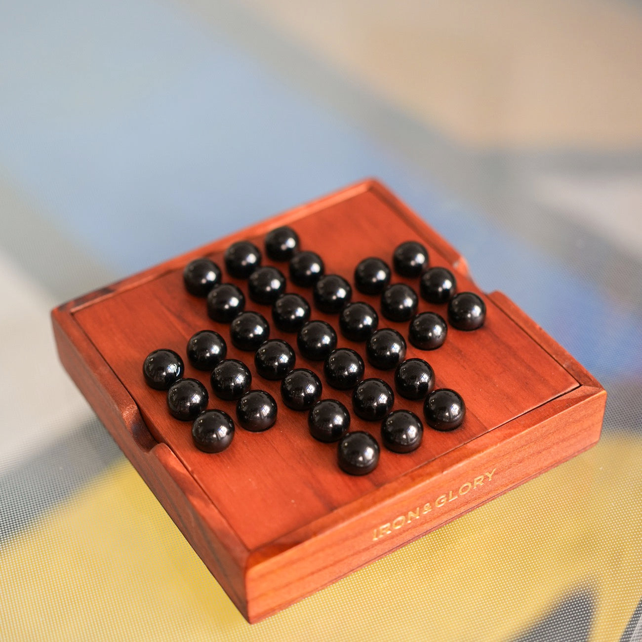 Solitaire en bois avec billes de verre sur un fond clair.