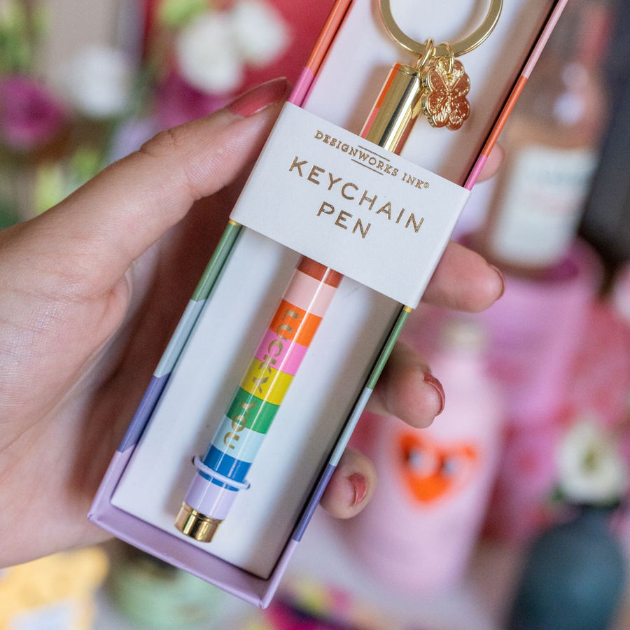 Porte-clé avec stylo rayé et trèfle doré, vue de près.