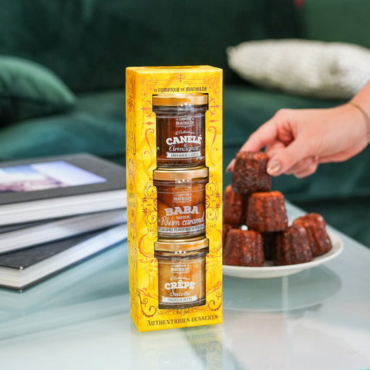 Coffret de desserts avec baba, canelé et crêpes en vue aérienne.