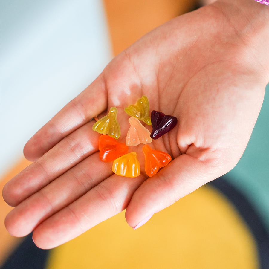Bonbons en forme de clitoris colorés et sucrés sur fond blanc.
