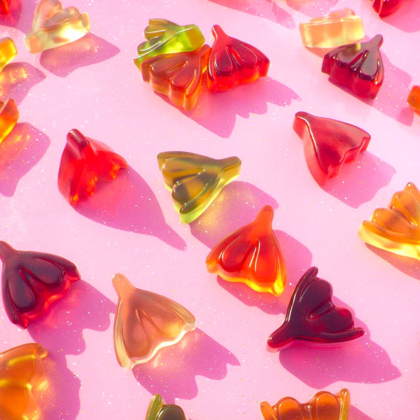 Bonbons en forme de clitoris colorés sur fond blanc