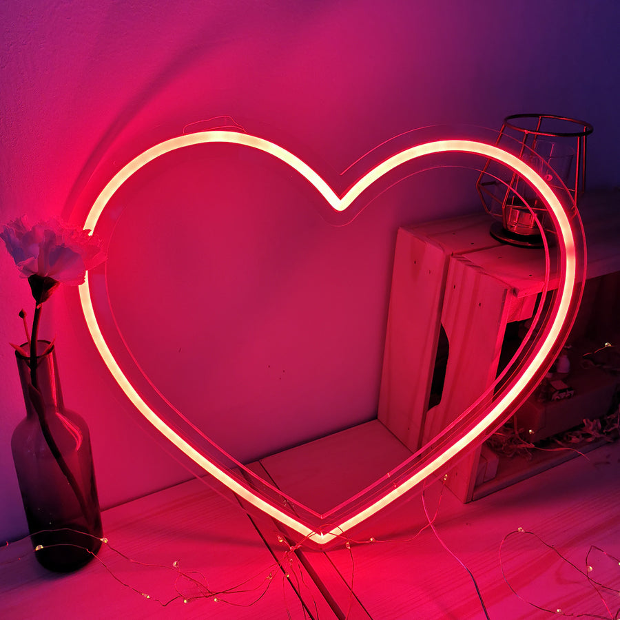 Néon en forme de cœur rouge lumineux sur fond neutre.