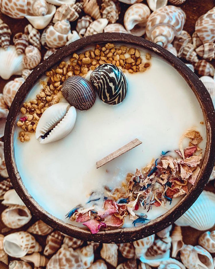 Bougie au monoï dans une noix de coco avec fleurs séchées
