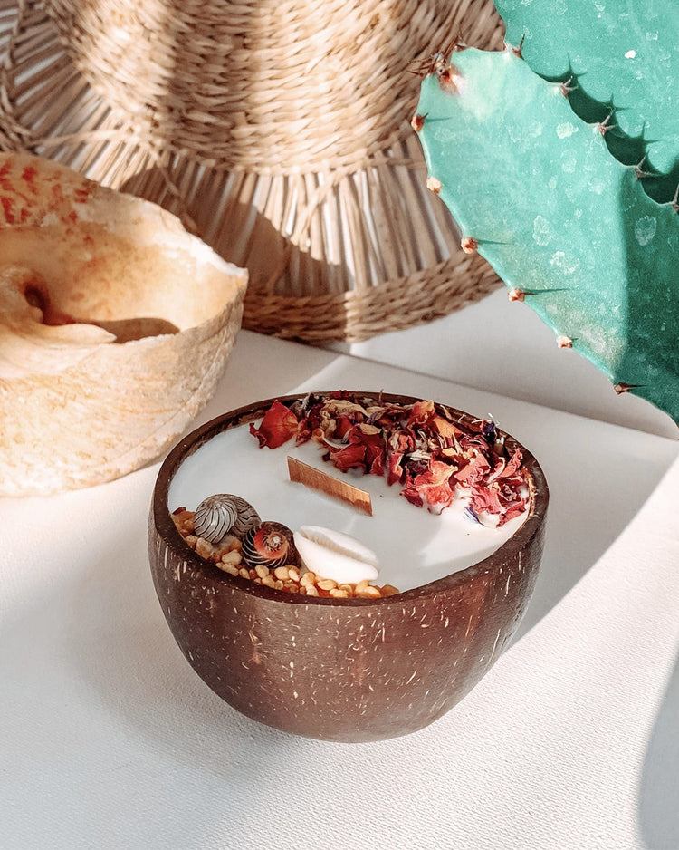 Bougie au monoï dans une noix de coco avec fleurs séchées