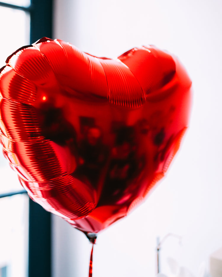 Ballon en forme de cœur rouge, texture lisse et brillante.
