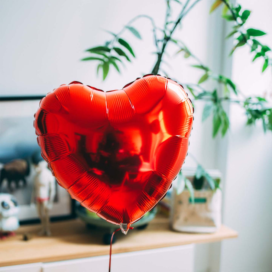 Ballon en forme de cœur rouge flottant avec une carte personnalisée.