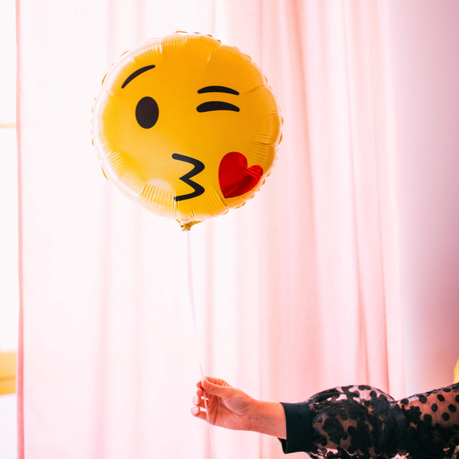 Ballon Emoji Bisous en forme de coeur rouge avec visage souriant, idéal pour exprimer l'amour et l'affection.