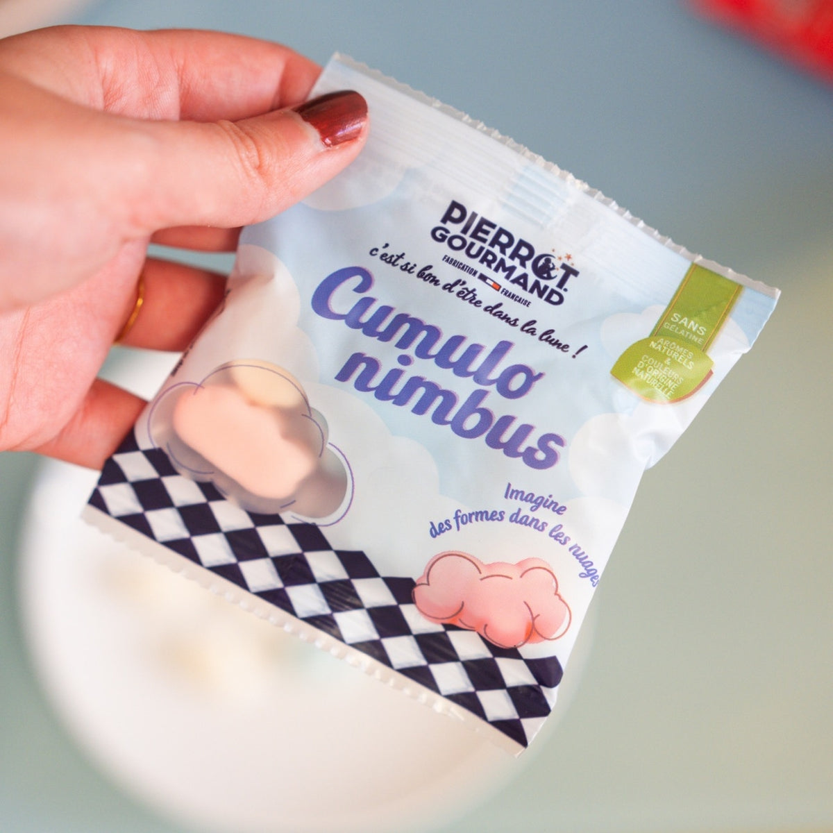 Sachet de guimauves nuage tenu en main, décoré d’un motif à damier