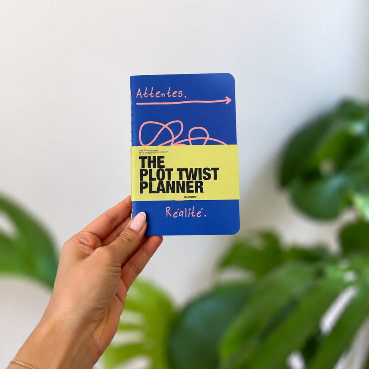 Agenda bleu tenu en main, avec une flèche rose et une bande jaune vif