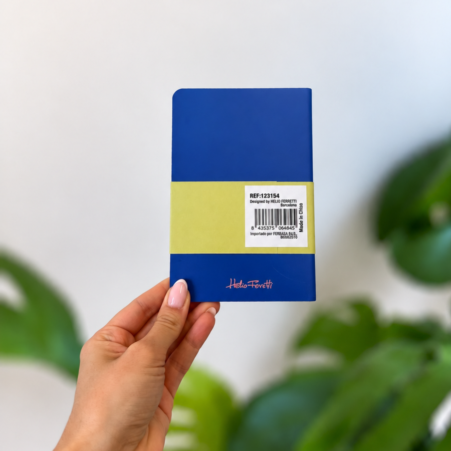 Agenda compact bleu tenu en main, avec bande jaune et étiquette au dos