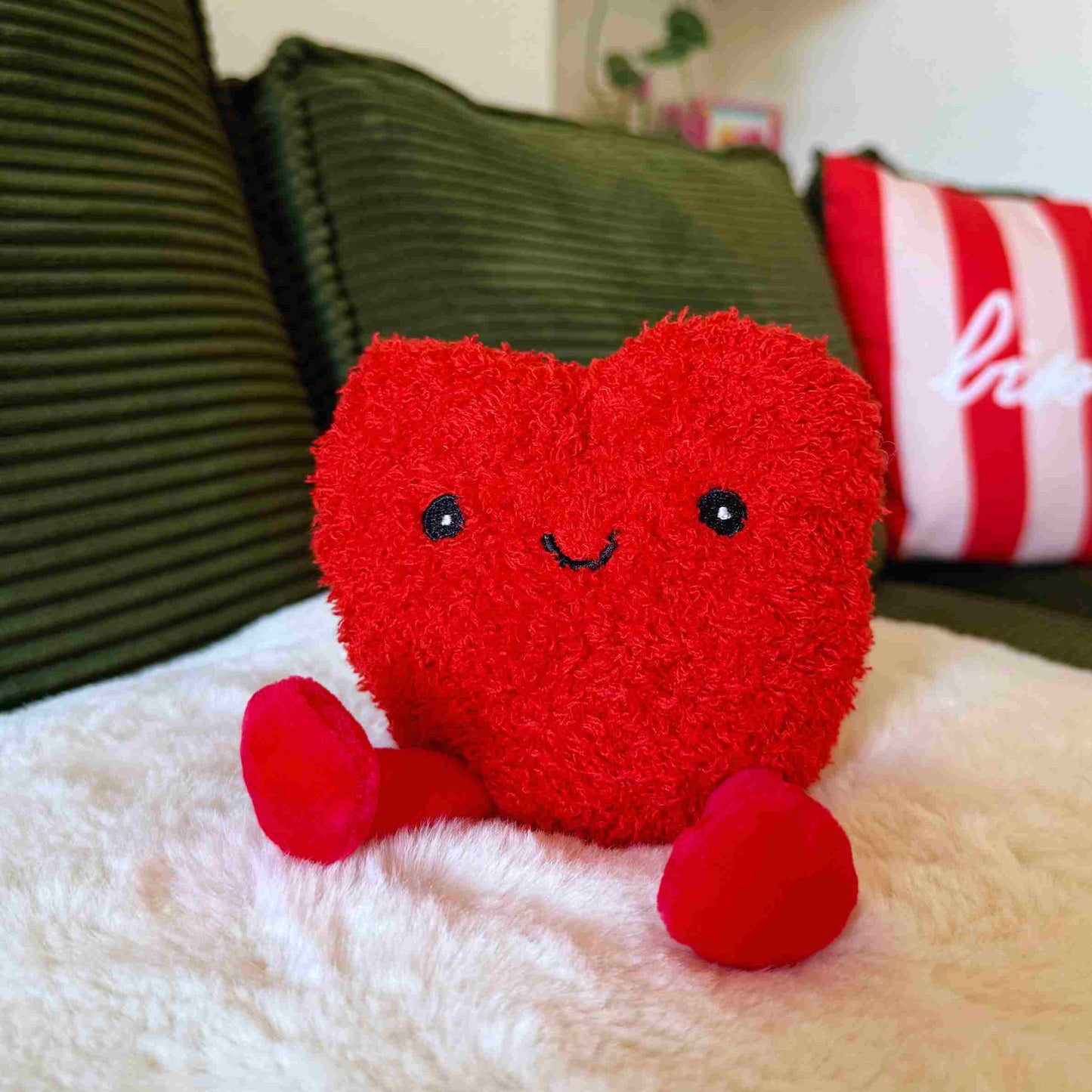 Bouillotte en forme de cœur avec pattes douces et regard affectueux.