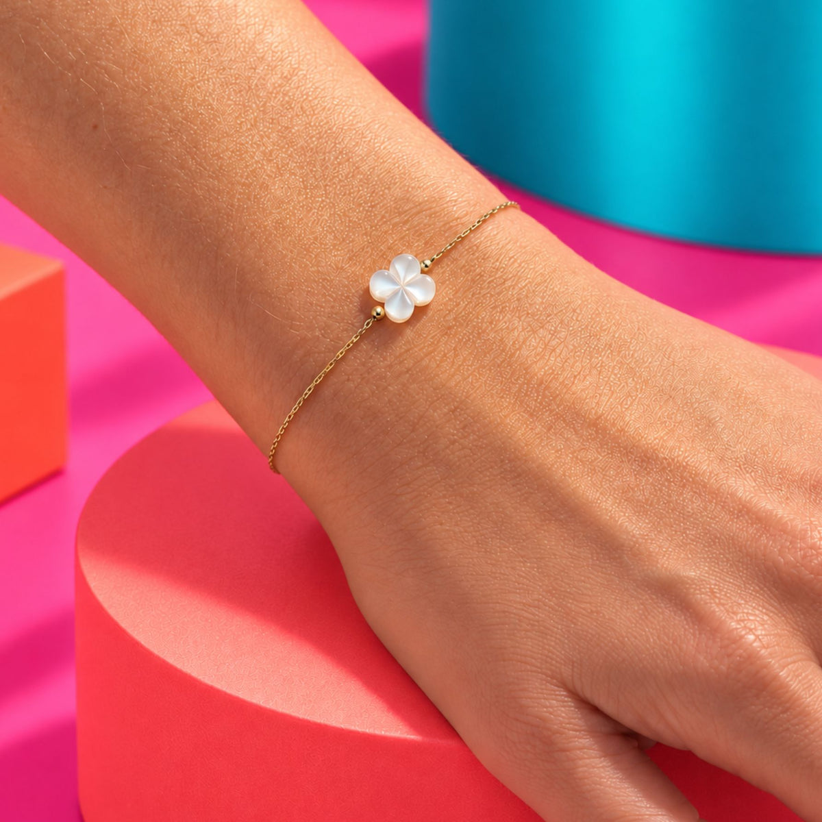 Bracelet doré à trèfle nacré bombé, porté en gros plan au poignet