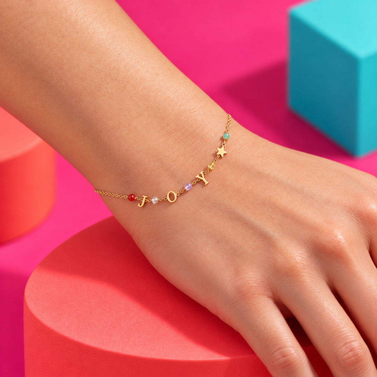 Bracelet doré JOY aux perles colorées et étoile, porté au poignet