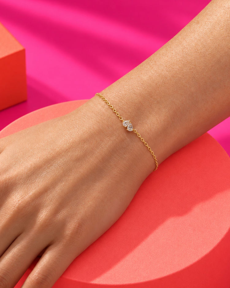 Bracelet fin doré à deux pierres claires porté au poignet