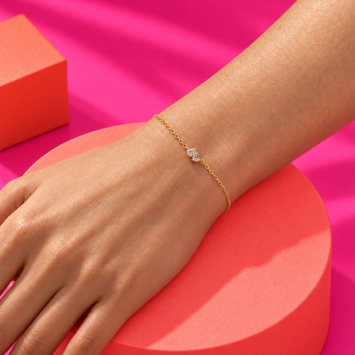 Bracelet fin doré à deux pierres claires porté au poignet