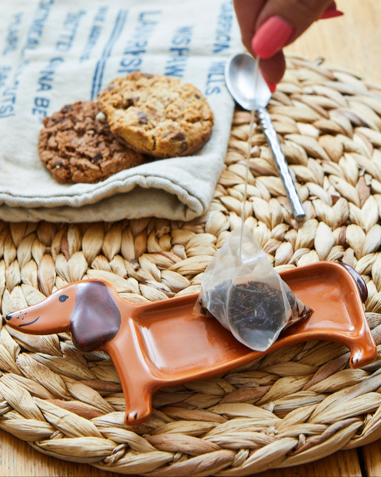 Repose thé en forme de teckel avec détails en bois naturel.