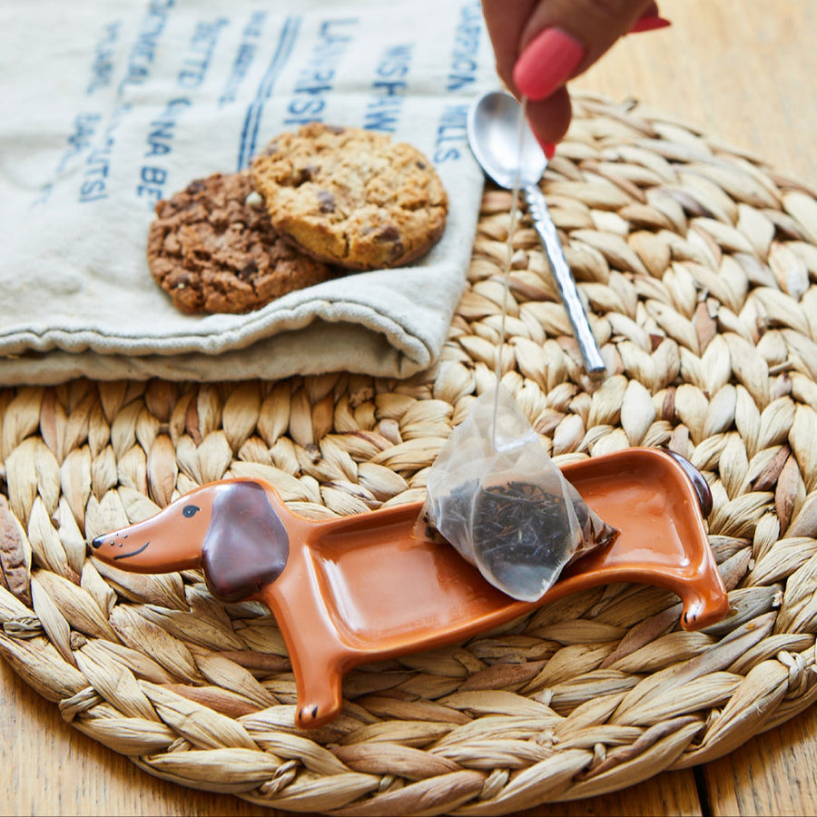 Repose thé en forme de teckel avec détails en bois naturel.
