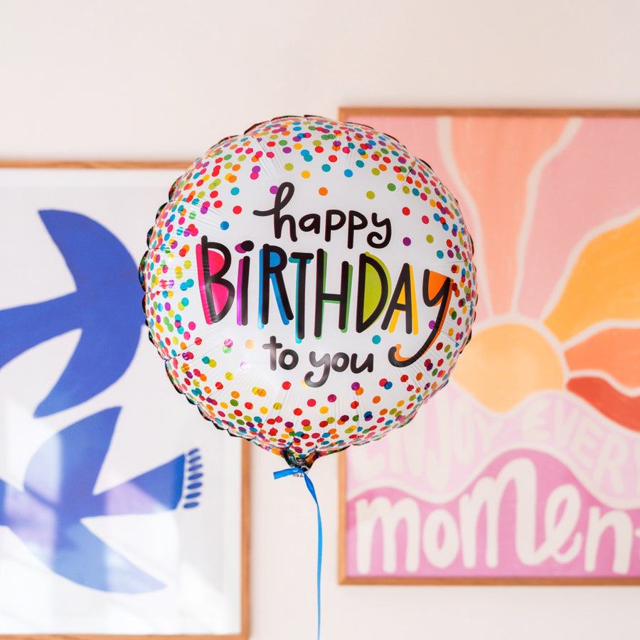 Ballon 'Happy Birthday' avec confettis colorés en gros plan.