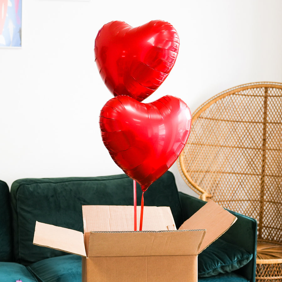 Box contenant deux ballons en forme de cœur rouge.