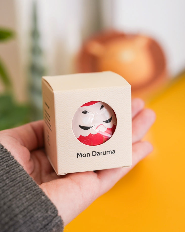 Daruma japonais en boîte, motif traditionnel et coloré.
