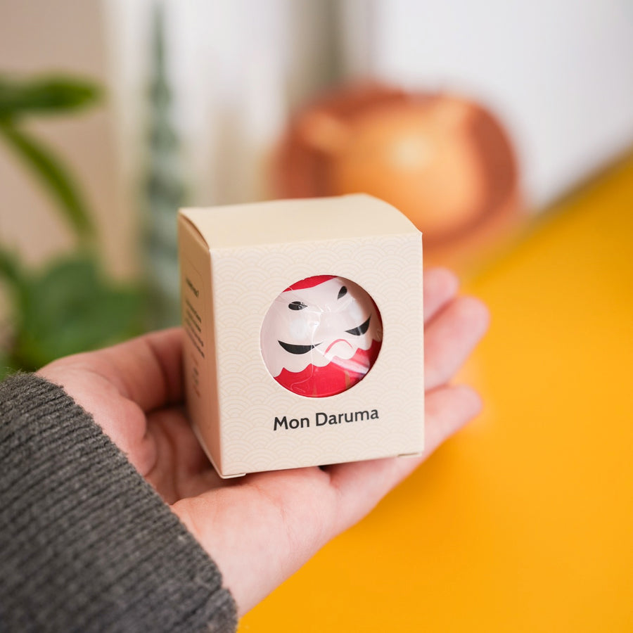 Daruma japonais en boîte, motif traditionnel et coloré.