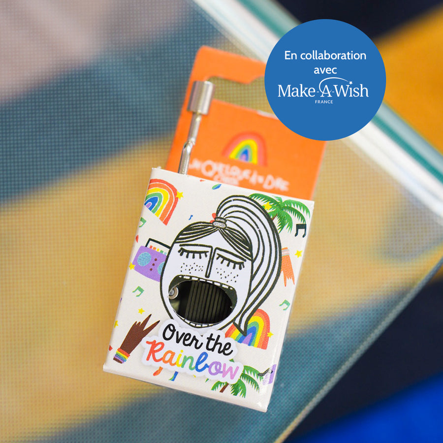 Boîte à musique avec motif coloré et manivelle visible.