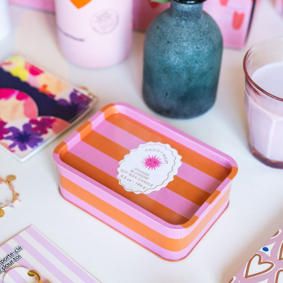 Bougie à 2 mèches avec rayures orange et rose, motif soleil.