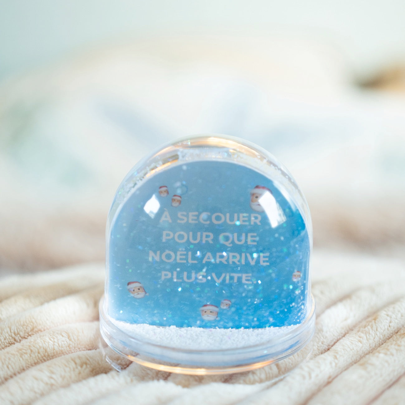 Boule à neige avec flocons scintillants et décor festif.