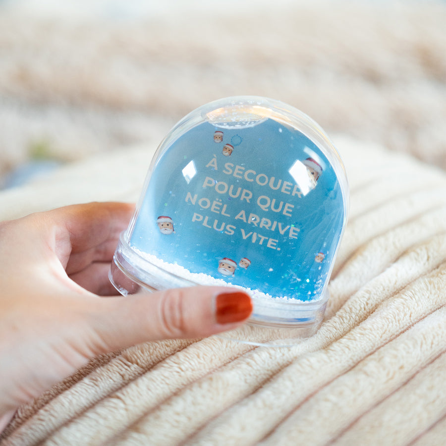 Boule à neige avec flocons scintillants et décor festif.