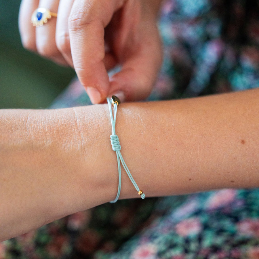 Bracelet porte-bonheur avec fleur nacrée et cordon tressé