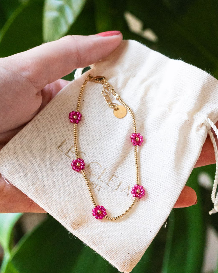Bracelet avec marguerites roses et détails dorés en gros plan.